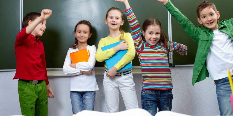 Portrait of five pupils having fun in classroom